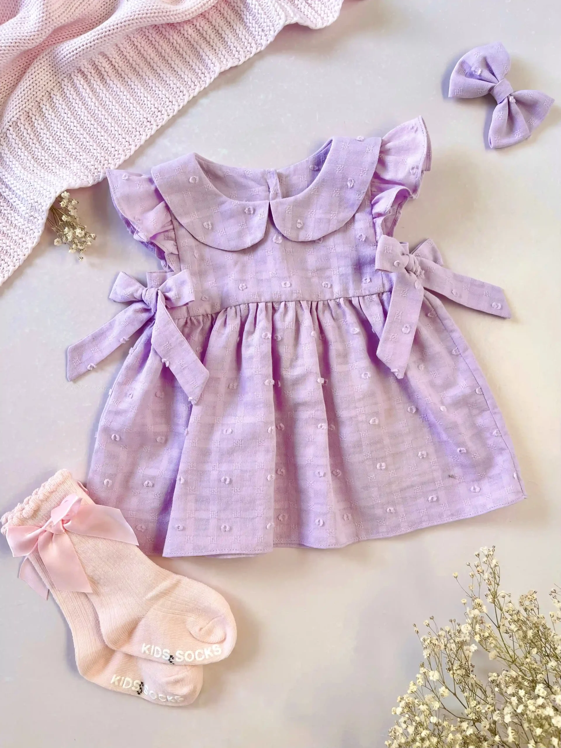 Vestido lila para bebé niña en tela bordada con lazos - Imagen 4