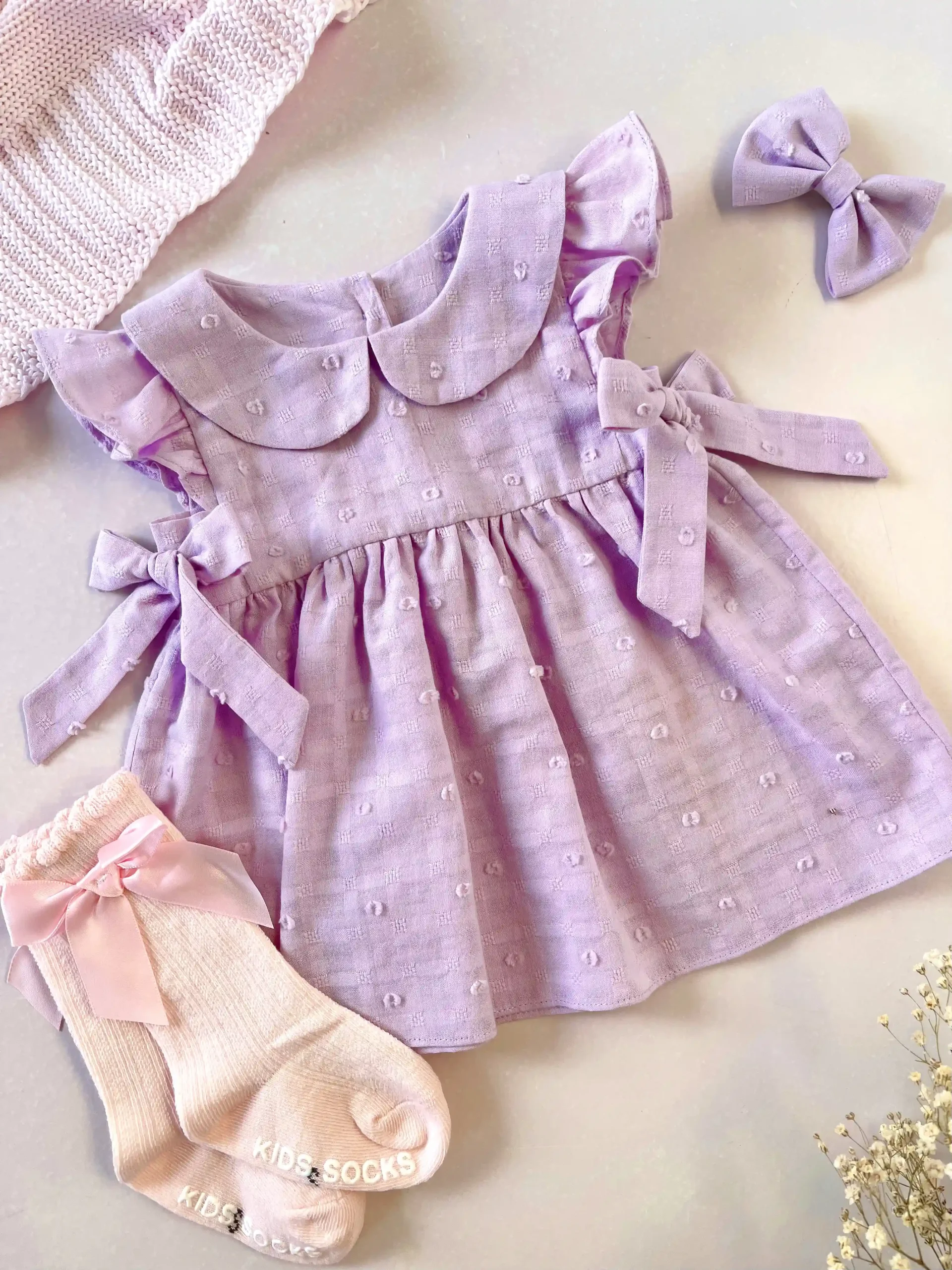 Vestido lila para bebé niña en tela bordada con lazos - Imagen 3