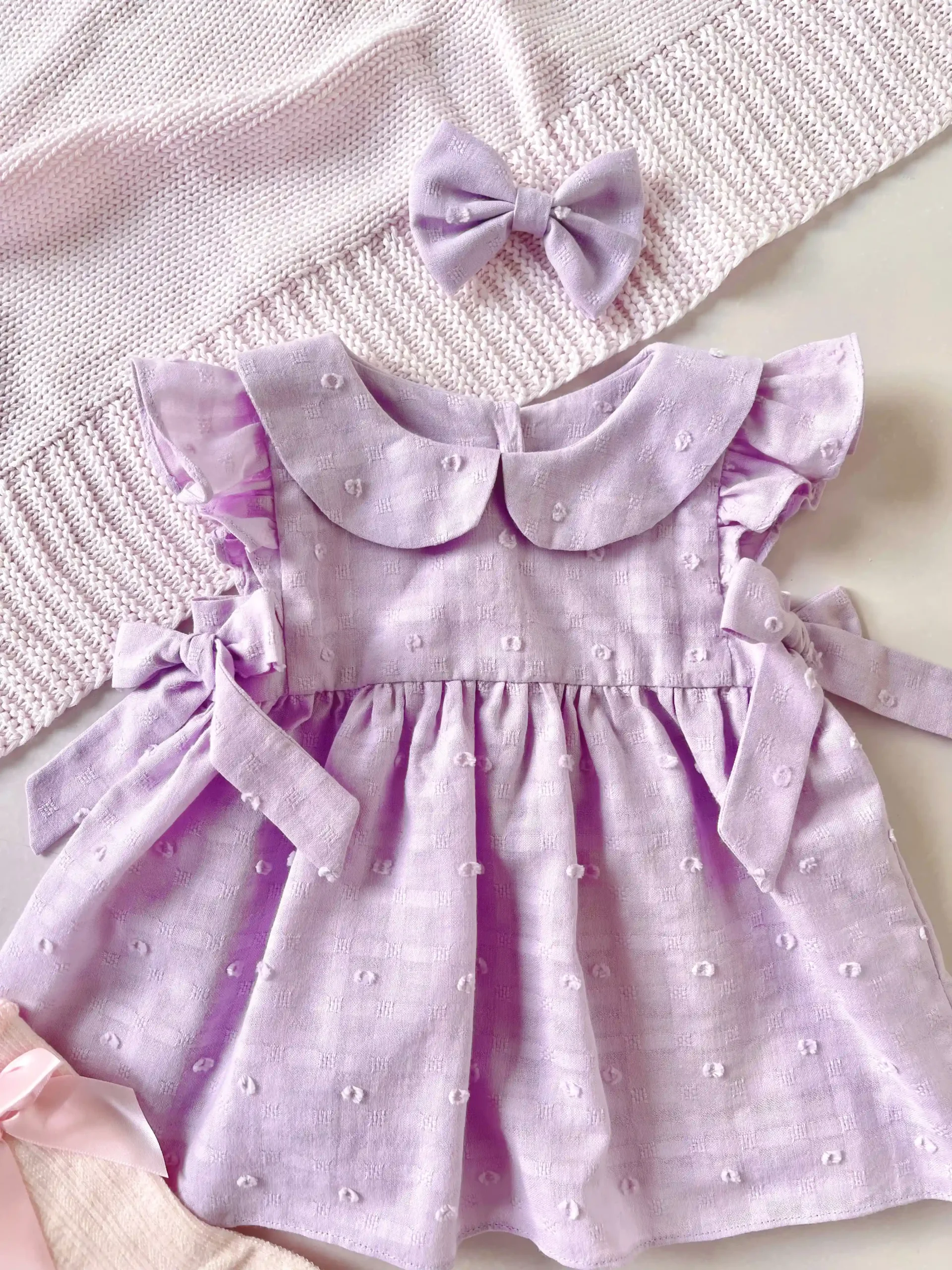 Vestido lila para bebé niña en tela bordada con lazos - Imagen 2